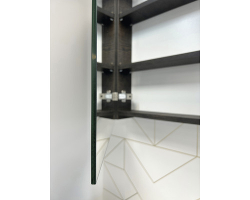 Gros plan d''une armoire de toilette avec étagère en verre et cadre en bois foncé sur un mur blanc avec motif carrelé