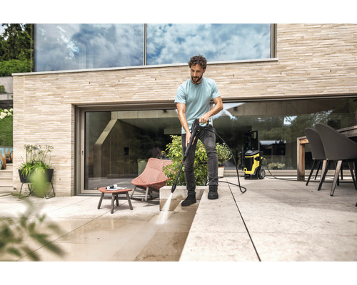 Un homme nettoie une terrasse avec un nettoyeur haute pression