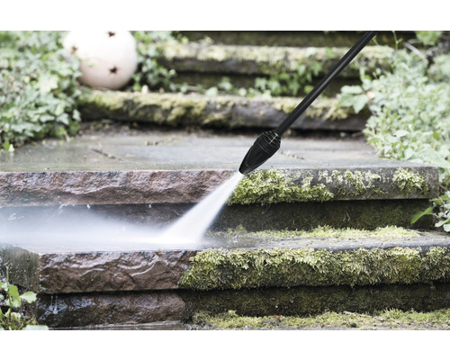 Un nettoyeur haute pression nettoie un escalier en pierre de la mousse.