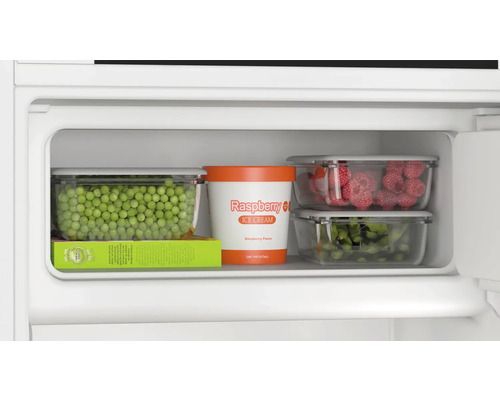 Compartiment congélateur avec petits pois, glace à la framboise, framboises et haricots verts dans des conteneurs de stockage