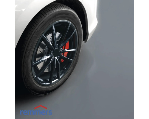 Gros plan d''un pneu de voiture avec jante sur un sol de garage.