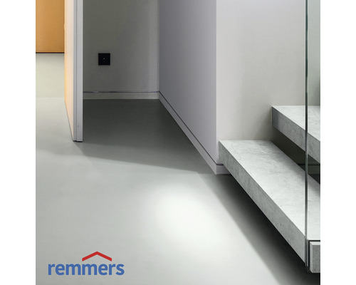 Heller Raum mit Betonboden und Treppe mit Glasgeländer. Remmers Logo.