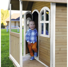 Enfant dans une cabane de jeux en bois dans le jardin