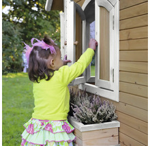 Un enfant ouvre une fenêtre d''une cabane de jeux en bois avec jardinière.