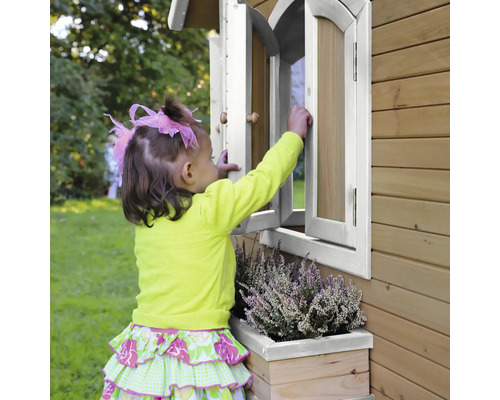 Un enfant ouvre une fenêtre d''une cabane de jeux en bois avec jardinière.