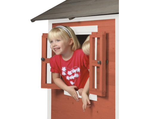 Fille regardant par la fenêtre d''une cabane en bois