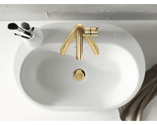 Vue de dessus d''un lavabo avec robinetterie dorée, un support avec des pinceaux de maquillage et une serviette