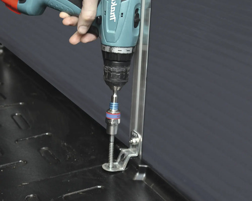 Eine Person verwendet einen Akkuschrauber zum Festschrauben eines Winkels.