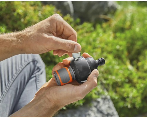 Une personne insère une pièce dans un programmateur d''arrosage.