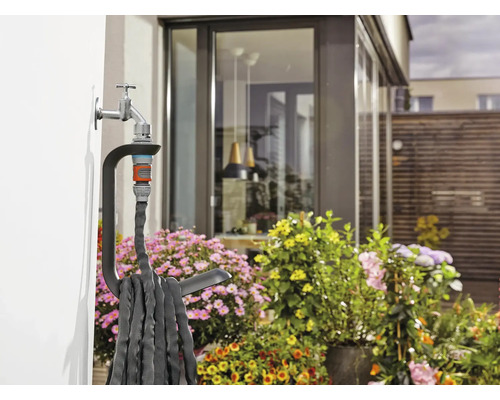 Tuyau d''arrosage avec support sur le robinet sur un mur de maison dans le jardin