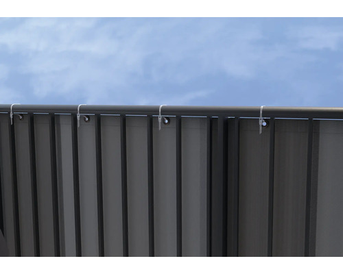 Metallzaun mit Ösen und Kabelbindern unter blauem Himmel