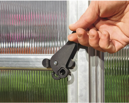 Main actionnant le loquet de fermeture sur une fenêtre de serre