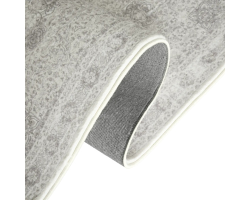 Detailansicht eines gemusterten Teppichs mit gekrempelter Ecke, der die Unterseite zeigt