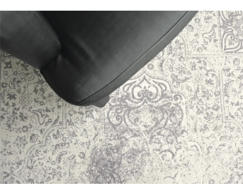 Detailaufnahme eines Teppichs mit floralem Muster und einem Teil eines Sessels