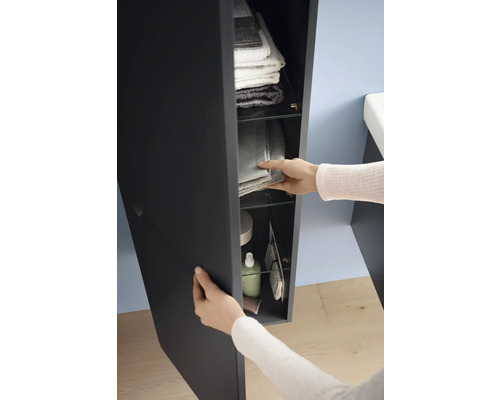 Person öffnet einen Badezimmerschrank mit Handtüchern und Pflegeprodukten auf Glasböden