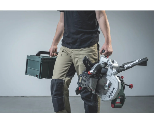 Eine Person trägt eine Metabo Kappsäge und einen Werkzeugkoffer.