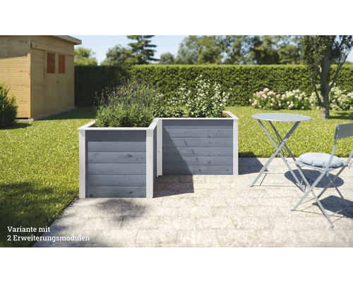 Deux bacs à fleurs surélevés en bois gris avec des plantes dans le jardin, à côté d''une table de jardin avec une chaise.