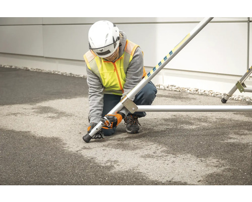 Une personne monte un échafaudage avec des pieds de nivellement.