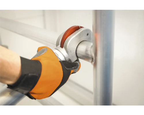 Une personne fixe une barre d''échafaudage avec un raccord de tuyau