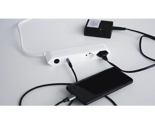 Mehrfachsteckdose mit angeschlossenen Geräten wie einem Smartphone und einem Netzteil