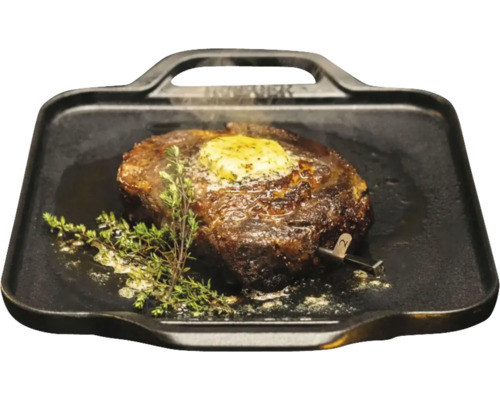 Steak sur une plaque de grill avec du beurre et du thym