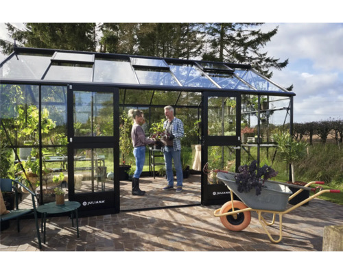 Gewächshaus mit zwei Personen und einer Schubkarre im Garten.