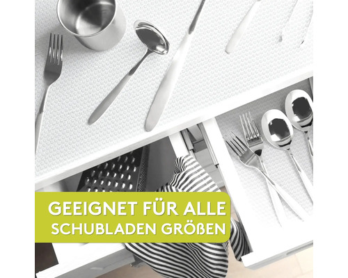 Vue dans un tiroir avec un tapis antidérapant et divers ustensiles de cuisine.