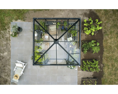 Draufsicht eines Gewächshauses mit Pflanzen und Gartenmöbeln auf einer Terrasse.