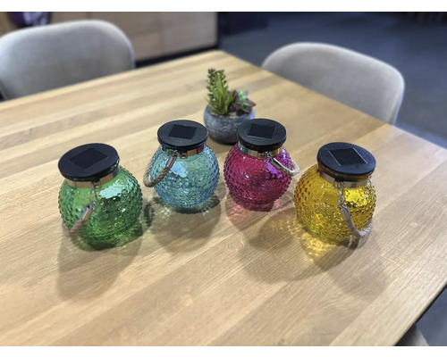 Quatre lanternes solaires en verre avec dragonne sur une table