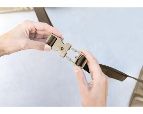 Les mains attachent une boucle en plastique sur une sangle