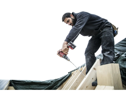 Un homme fixe des chevrons avec une visseuse sans fil.