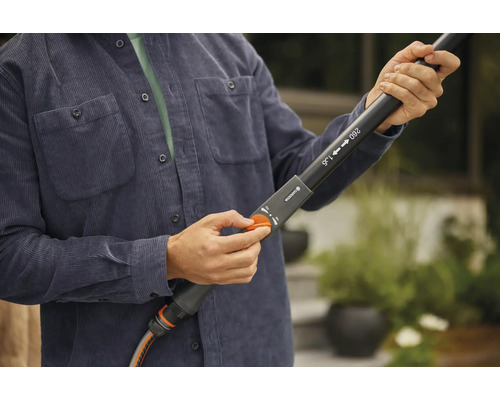 Person reguliert Gartenschlauch an einer Teleskoplanze