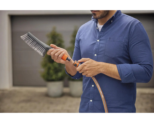 Mann schliesst Bürste an Gartenschlauch an