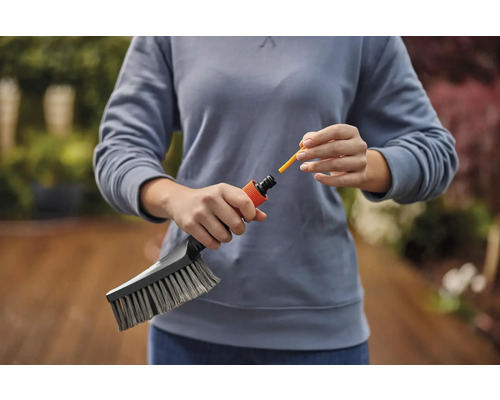 Eine Person verbindet eine Waschbürste mit einem Gartenschlauchanschluss.