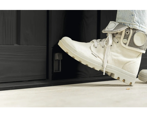 Person öffnet mit dem Fuss eine schwarze Aussentür mit Drehknopf