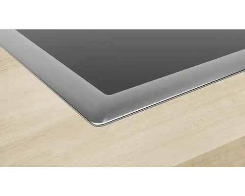 Vue détaillée d''une plaque de cuisson avec cadre en acier inoxydable sur un plan de travail.