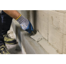 Handwerker trägt Putz mit einer Maurerkelle auf eine Wand auf
