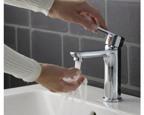 Une femme se lave les mains sous un mitigeur de lavabo chromé.