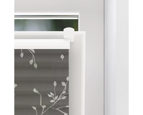 Gros plan d''un store plissé gris avec motif de feuilles sur une fenêtre