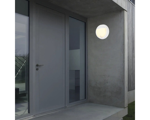 Runde weisse Aussenleuchte an einer Hauswand neben einer Tür