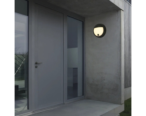 Aussenansicht eines Hauses mit einer runden Wandleuchte neben der Tür