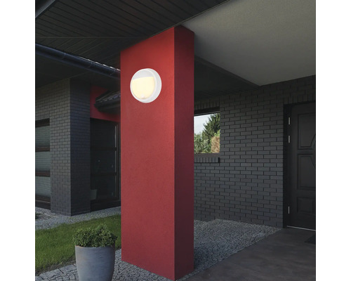 Runde Aussenleuchte an roter Säule vor einem Haus.