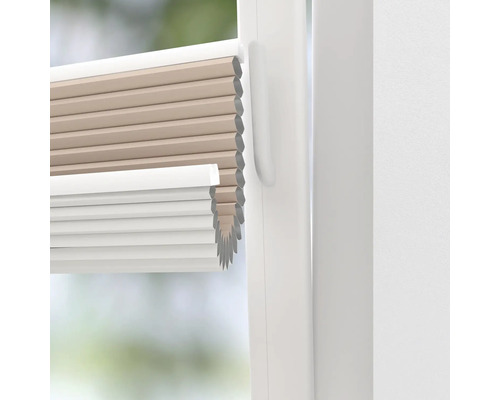 Gros plan d''un store plissé beige et blanc sur une fenêtre