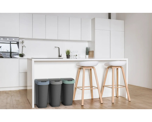 Trois poubelles dans une cuisine moderne avec îlot et tabourets de bar.