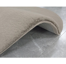 Vue détaillée d''un tapis beige à poils longs sur un sol carrelé.