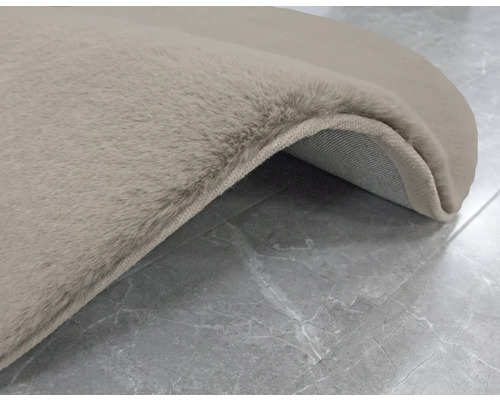 Vue détaillée d''un tapis beige à poils longs sur un sol carrelé.