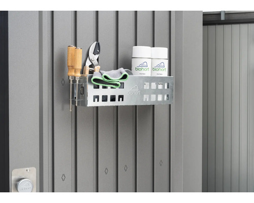 Étagère avec outils de jardinage et sprays sur un mur gris