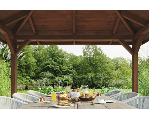 Table dressée sous un pavillon de jardin en bois avec vue sur le jardin