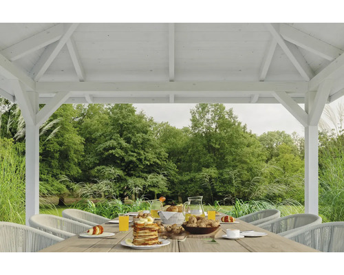 Scène dans un pavillon de jardin avec une table dressée et vue sur la verdure
