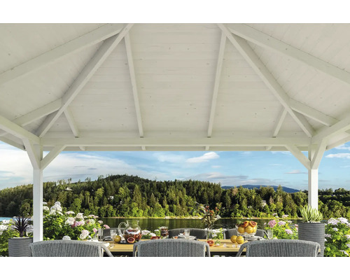 Weisser Holzpavillon mit Tisch und Stühlen im Freien mit Seeblick.